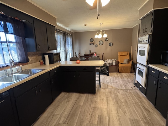 kitchen featuring black microwave, a sink, light countertops, ornamental molding, and light wood-type flooring