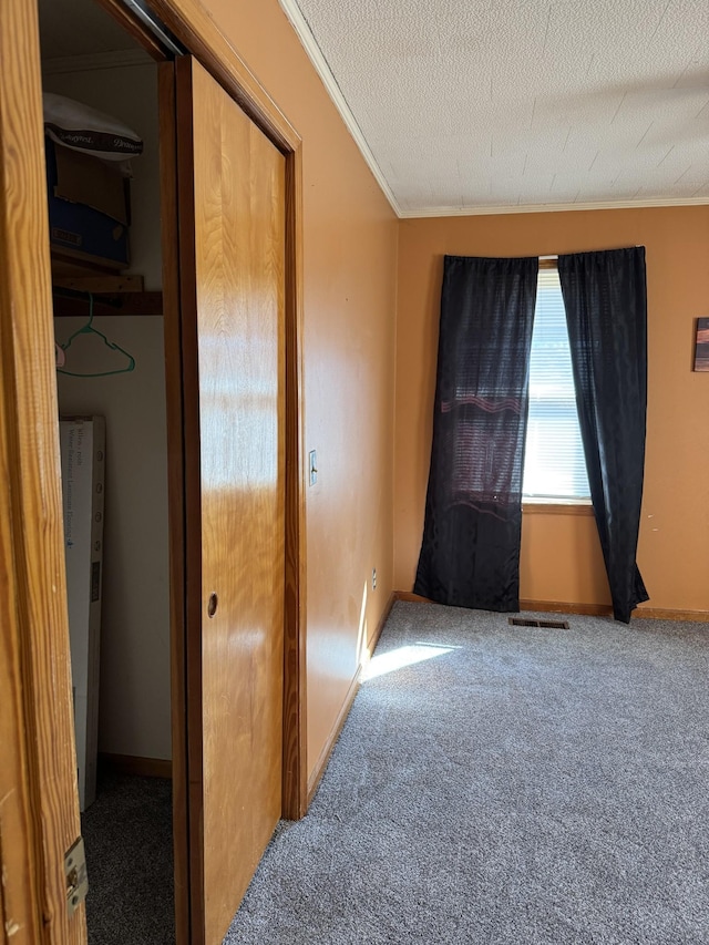 spare room with carpet flooring, crown molding, a textured ceiling, and baseboards