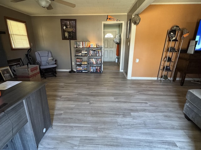 interior space with baseboards, a ceiling fan, crown molding, and wood finished floors