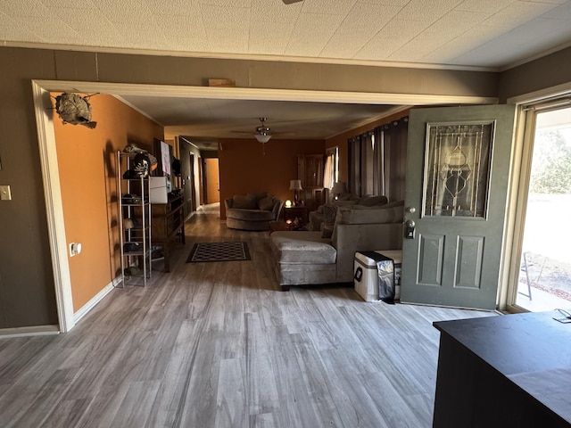 foyer entrance with a ceiling fan, wood finished floors, and ornamental molding