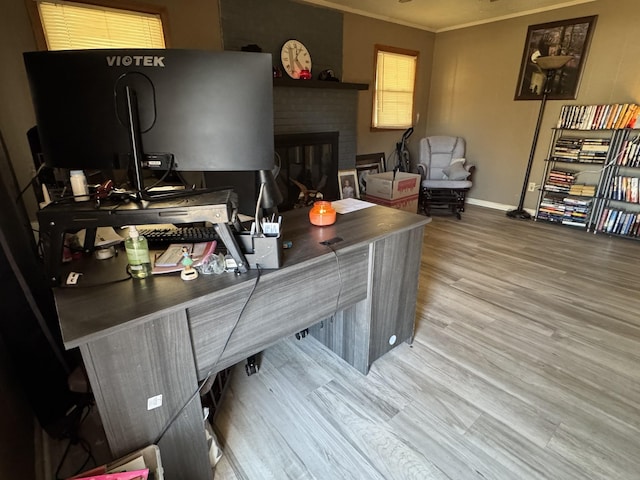 office area with baseboards, a fireplace, ornamental molding, and wood finished floors