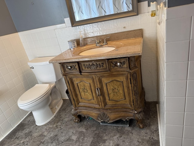 bathroom with toilet, wainscoting, tile walls, and vanity