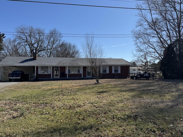 ranch-style house featuring driveway, brick siding, a chimney, an attached carport, and a front yard