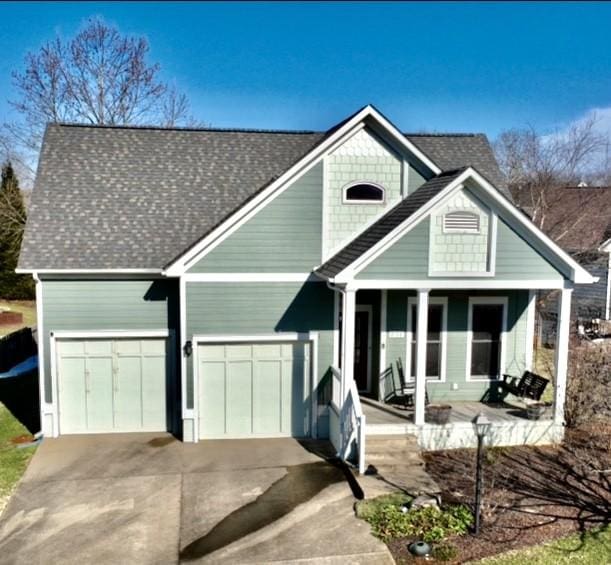 view of front facade featuring a porch, driveway, and a shingled roof