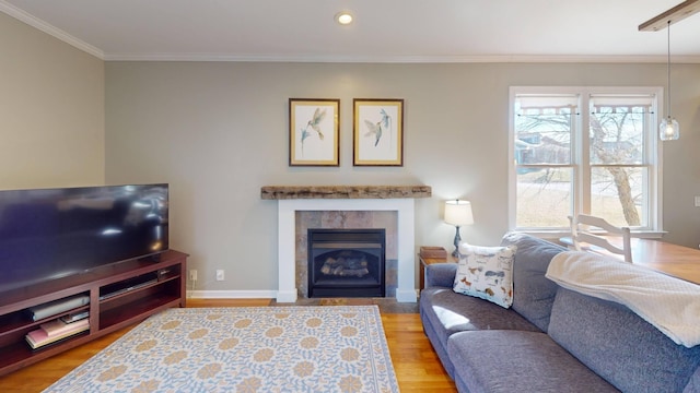 living room featuring wood finished floors, baseboards, recessed lighting, a tile fireplace, and crown molding