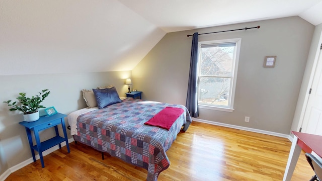 bedroom featuring baseboards, wood finished floors, and vaulted ceiling