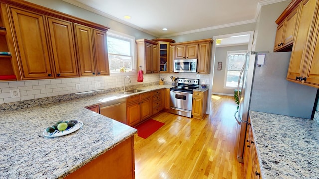 kitchen with brown cabinetry, appliances with stainless steel finishes, crown molding, and a sink