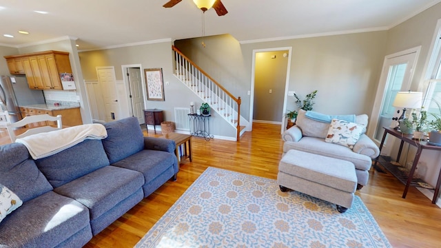 living area with crown molding, stairway, and light wood-type flooring