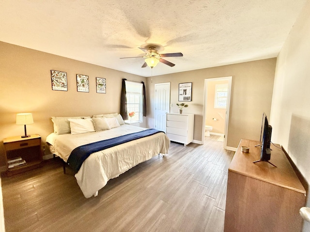 bedroom featuring baseboards, a ceiling fan, wood finished floors, ensuite bathroom, and a textured ceiling