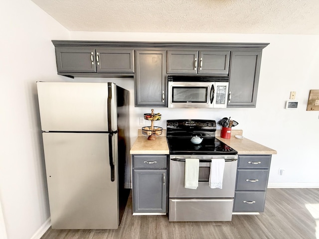 kitchen featuring appliances with stainless steel finishes, light countertops, light wood finished floors, and gray cabinetry