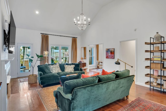 living room with baseboards, a notable chandelier, high vaulted ceiling, and wood finished floors