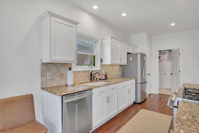 kitchen featuring tasteful backsplash, white cabinets, dark wood finished floors, stainless steel appliances, and a sink