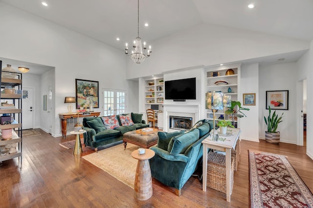 living area featuring high vaulted ceiling, a glass covered fireplace, and wood finished floors