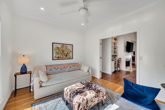 living room featuring crown molding, a ceiling fan, and wood finished floors