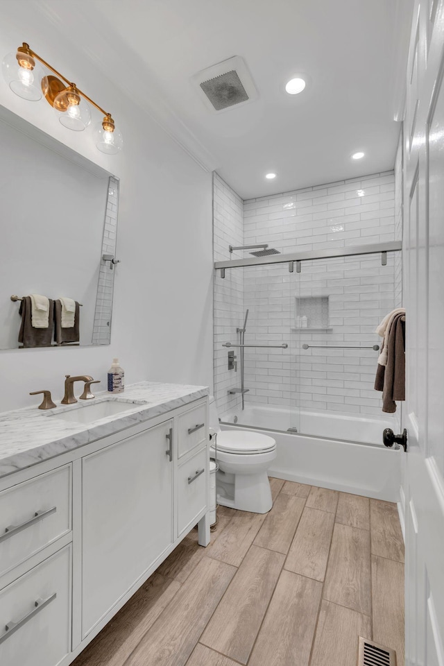 bathroom featuring enclosed tub / shower combo, visible vents, vanity, and toilet