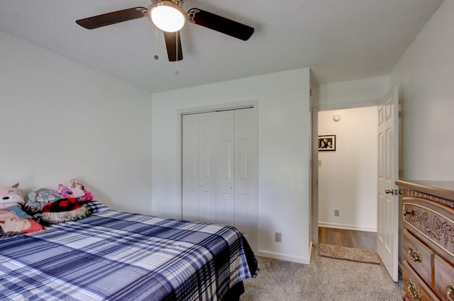 carpeted bedroom with ceiling fan, baseboards, and a closet