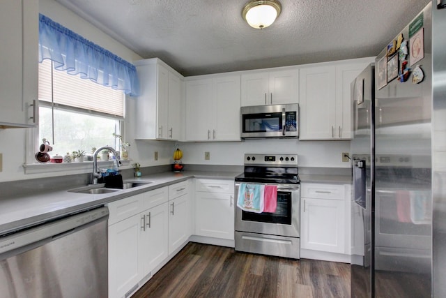 kitchen featuring dark wood-style floors, stainless steel appliances, light countertops, white cabinets, and a sink