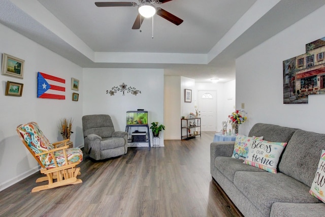 living room with a raised ceiling, wood finished floors, a ceiling fan, and baseboards