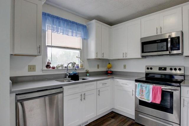 kitchen featuring a sink, white cabinetry, light countertops, appliances with stainless steel finishes, and dark wood finished floors