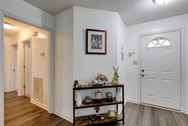 entryway featuring visible vents, a textured ceiling, baseboards, and wood finished floors