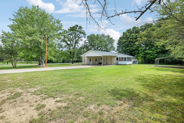 view of front of home featuring a carport, a sunroom, driveway, and a front lawn