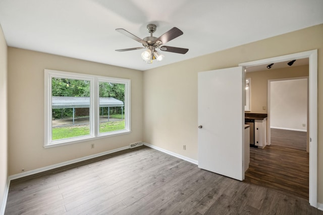 spare room with dark wood-style floors, ceiling fan, visible vents, and baseboards