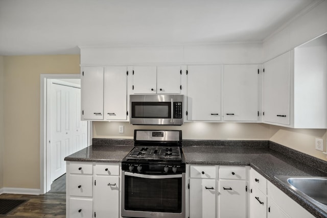 kitchen with baseboards, white cabinets, dark wood finished floors, appliances with stainless steel finishes, and a sink