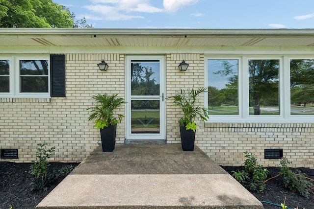 view of exterior entry featuring brick siding and crawl space