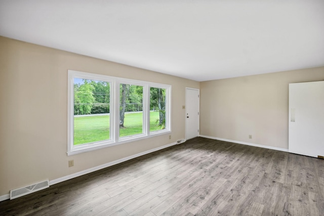 empty room with baseboards, visible vents, and wood finished floors