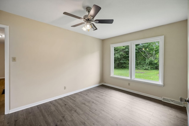 spare room featuring baseboards, visible vents, ceiling fan, and dark wood-style flooring