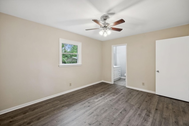 unfurnished bedroom featuring ceiling fan, ensuite bath, baseboards, and wood finished floors