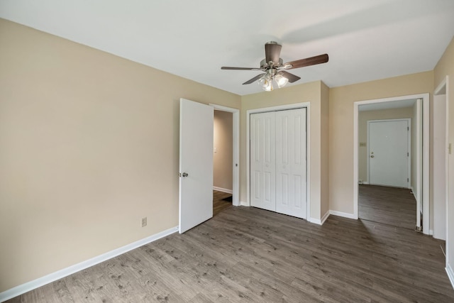 unfurnished bedroom featuring a closet, wood finished floors, a ceiling fan, and baseboards