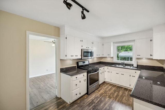 kitchen featuring dark wood-style floors, appliances with stainless steel finishes, a sink, and white cabinetry