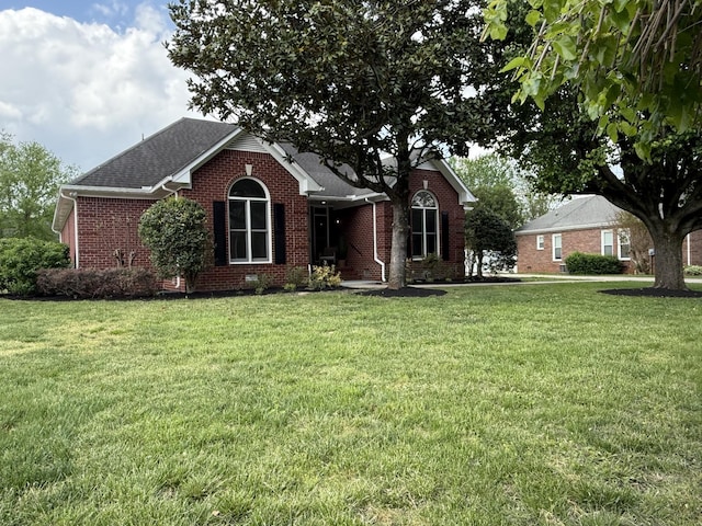 ranch-style house featuring brick siding, a front yard, and roof with shingles