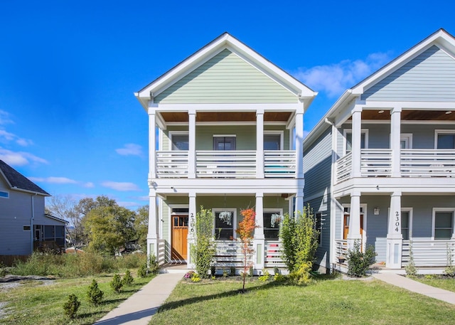 view of front facade featuring covered porch, a front lawn, and a balcony