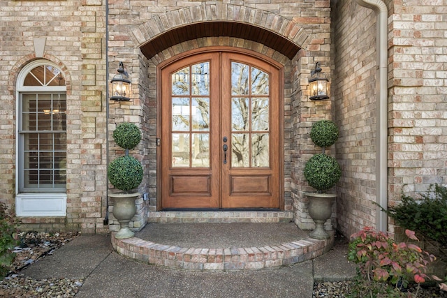 property entrance featuring stone siding, french doors, and brick siding