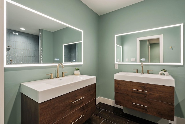 full bath featuring a sink, baseboards, and two vanities