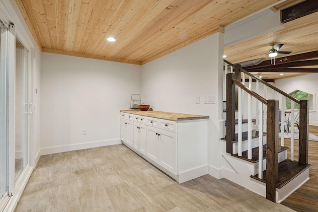 interior space with light wood-style flooring, wood counters, wood ceiling, and white cabinets