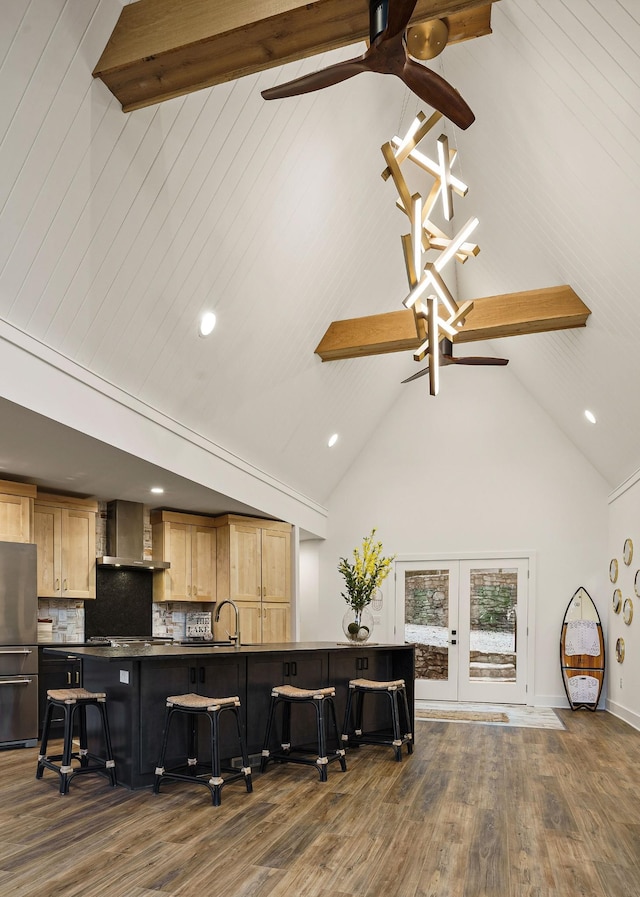 kitchen with freestanding refrigerator, beamed ceiling, wall chimney range hood, and dark countertops