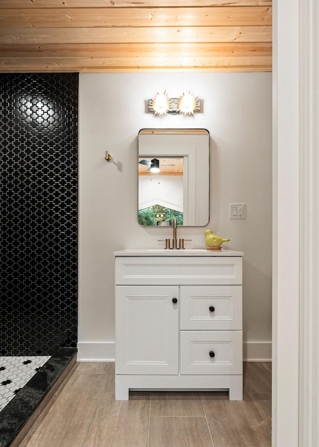 bathroom with baseboards, a shower stall, vanity, and wood finished floors