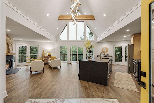 living room with light wood-style flooring, beamed ceiling, french doors, a fireplace, and high vaulted ceiling