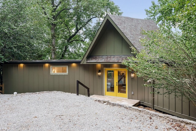 exterior space with board and batten siding, french doors, and roof with shingles