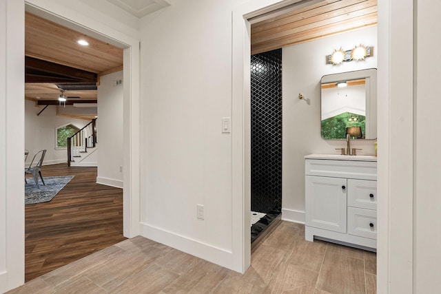 interior space featuring a shower, vanity, wood finished floors, wooden ceiling, and baseboards