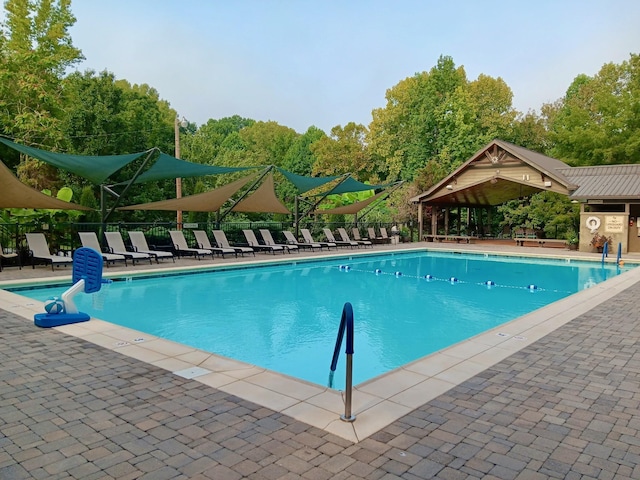 community pool with a patio area and fence