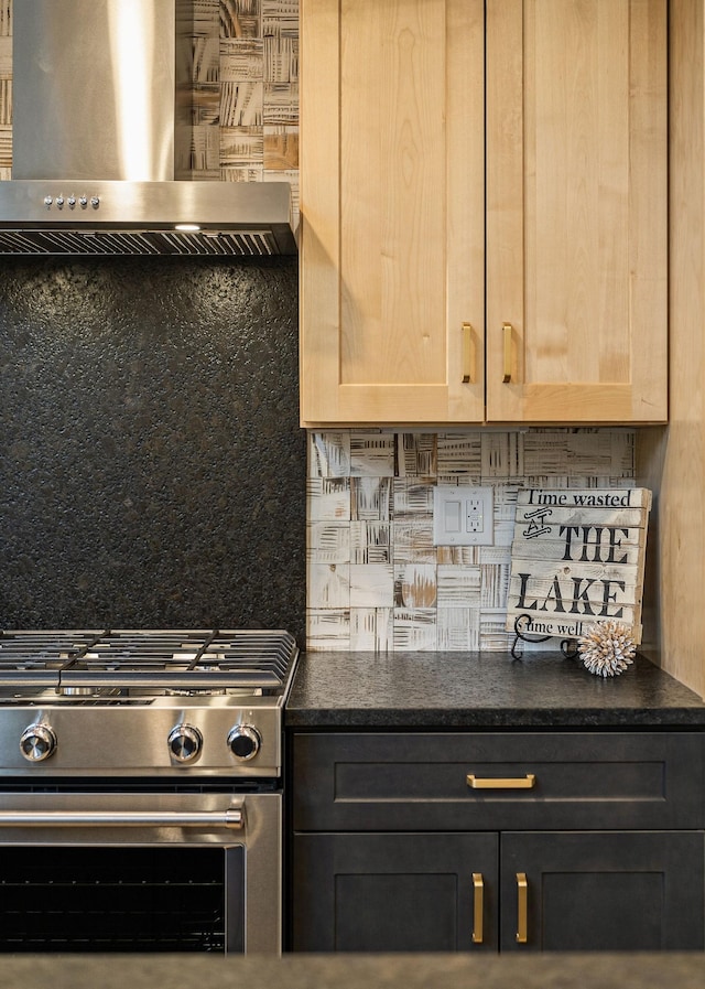 kitchen with wall chimney range hood, tasteful backsplash, stainless steel range with gas stovetop, and light brown cabinetry