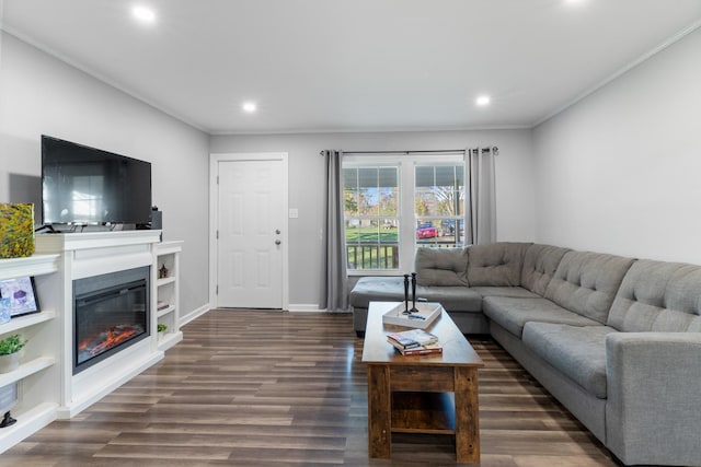 living room with baseboards, a glass covered fireplace, ornamental molding, dark wood-type flooring, and recessed lighting