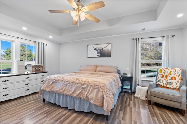 bedroom with ceiling fan, a tray ceiling, wood finished floors, and recessed lighting