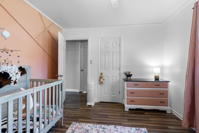 bedroom with a crib, baseboards, and dark wood-type flooring