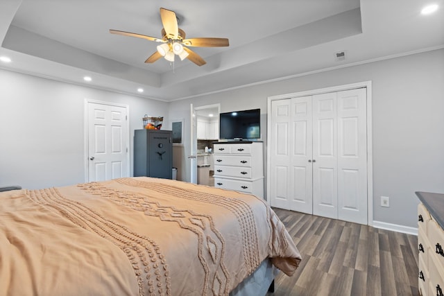 bedroom with recessed lighting, a raised ceiling, a closet, dark wood-type flooring, and baseboards