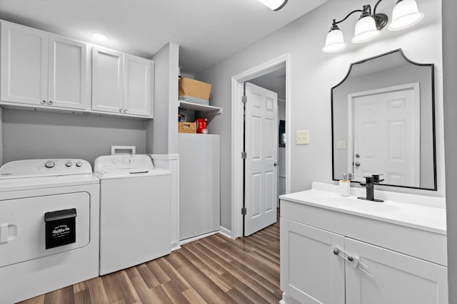 laundry area featuring wood finished floors, independent washer and dryer, a sink, and cabinet space